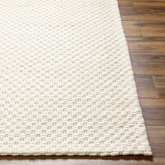 a white rug on the floor with wood floors in the background and a wooden floor