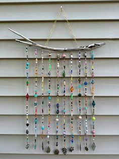 a wind chime hanging on the side of a house with beads and feathers attached to it