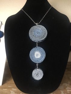 three necklaces on a black mannequin with blue beads hanging from it's sides