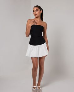 Introducing the Black Strapless Colorblock Flare Mini Dress, a chic and versatile piece that combines modern style with a playful silhouette. Featuring a sleek black strapless bodice that highlights the neckline and shoulders, the dress contrasts with a flared white skirt for a flattering colorblock design. The fitted top hugs the body, while the flared skirt adds movement and dimension, making it perfect for both casual and semi-formal occasions. Ideal for summer outings or evening events, this dress effortlessly balances elegance and fun. Heiress Beverly Hills, Corset Pants, Flare Mini Dress, Fitted Top, White Skirt, Flared Skirt, Blazer Dress, White Skirts, Xl Dress