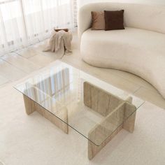 a living room with a white couch and glass coffee table in the middle of it