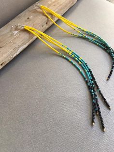 three strands of beaded necklaces with yellow and blue beads on a piece of driftwood