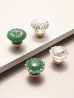 three green glass knobs sitting on top of a white shelf next to each other