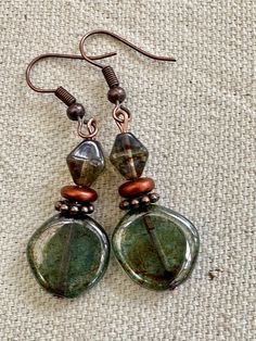 Beautiful  transparent Lumi green glass.  An earthy picasso coat is added giving earthy touches to the entire surface of the coin beads. They are beautiful coin beads. They have a matching 8mm beautiful and earthy pine green bicone glass bead.  They have a glossy fire polished lumi finish. The earrings dangle an inch on Copper Ear Wires.  The copper accents bring out the earthy feeling of these unique earrings. Perfect for work or casual anytime of year. UniquelybyRuth pays for your first class shipping when your order is $35 or more, so take a look around the shop and see if anything else calls to you! 🆓 Chip Bead Earrings, Earth Decor, Earthy Jewelry, Glass Bead Earrings, Belly Jewelry, Copper Accents, Stylish Earrings, Funky Jewelry, Pine Green