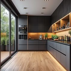 a modern kitchen with wooden floors and dark gray cabinetry is lit by recessed lighting