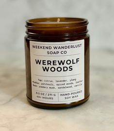 a candle that is sitting on top of a marble counter with a label reading, werewwolf woods