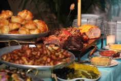 an assortment of food is displayed on a buffet table with blue cloths and plates