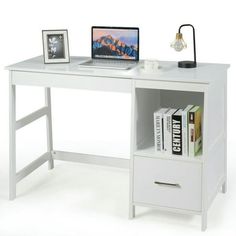 a computer desk with a laptop on top of it next to a book shelf and lamp