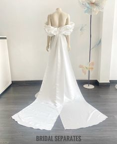 the back of a wedding dress on display in a room with white walls and flowers