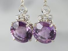 "Sophisticated and yet interesting, these earrings feature bright bursts of color from the amethysts and glittering white diamonds add sparkle. Simple metalwork between the diamonds and amethyst provides a wonderful sense of movement and allows these earrings to hang nicely from the ear. Sized to be noticed, these lovely earrings are sure to be a favorite for years to come! Metal: 14K White Gold Gem: 2 Amethyst totaling 26.39 Carats Gem Measurements: 14.9 mm, Round Accents: 8 Diamonds totaling . Earrings White Gold, Cameo Ring, Earrings White, Diamond Drops, Amethyst Earrings, Lovely Earrings, Diamond Drop Earrings, Elegant Earrings, White Diamonds