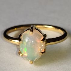 an opalite ring is shown on a white surface with gold trimmings