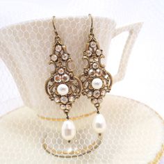 These gorgeous earrings I created with elegant European made antique brass filigree drops in which I placed Swarovski golden shadow crystals and Swarovski ivory pearls. Earrings dangle 2-3/4 inches from top of ear wire to bottom of pearl drop. PLEASE ALLOW APPROX 10 BUSINESS DAYS FOR COMPLETION BEFORE SHIPPING. This is an original design by © Treasures by Agnes Feel free to contact me with any questions ! Thank you for visiting ! Treasures570 Back to main page of Treasures570 for more beautiful Antique Finish Drop Earrings For Wedding, Antique Finish Bronze Wedding Earrings, Victorian Wedding Earrings With Antique Finish, Antique Bronze Earrings For Wedding, Vintage Gold Teardrop Crystal Earrings, Vintage Brass Chandelier Earrings For Wedding, Vintage Gold Crystal Earrings For Wedding, Vintage Gold Bridal Earrings For Wedding, Gold Vintage Crystal Earrings For Wedding