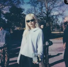 a woman standing in the street wearing sunglasses