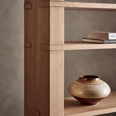 a wooden shelf with a vase and books on it