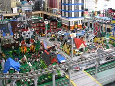 a model city with lots of buildings and cars on the tracks in front of it