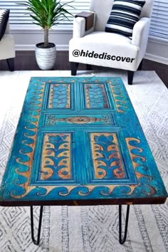 a coffee table that has been painted with blue and gold designs on it in a living room