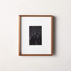 a black and white photo hanging on the wall next to a wooden frame with an image of two people holding hands