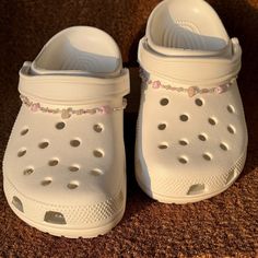 a pair of white shoes with holes on the bottom and sides, sitting on a brown carpet