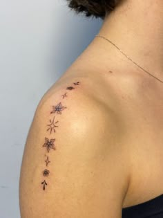 a woman with a tattoo on her shoulder that has stars and flowers all over it