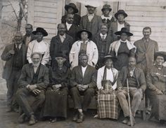 an old black and white photo of people in front of a house with hats on