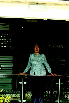 a woman standing in front of a window with her hands on the railing and smiling