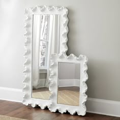 a white mirror sitting on top of a hard wood floor next to a window and rug