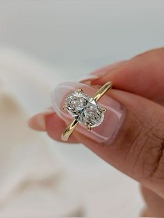 a woman's hand holding an engagement ring with a diamond in the middle and two diamonds on each side