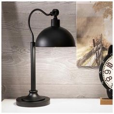 a black lamp sitting on top of a table next to a clock