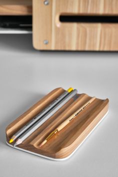 a wooden pen holder with three pencils in it