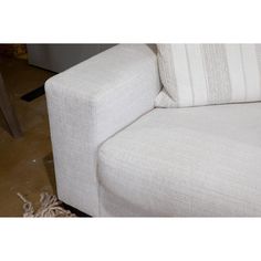 a white couch sitting on top of a floor next to a wooden table and chair