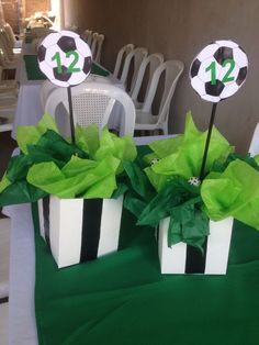 two black and white gift boxes with soccer balls on them sitting on a green table cloth