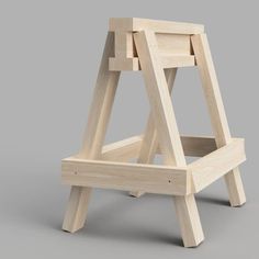 an unfinished wooden chair sitting on top of a gray floor next to a white wall