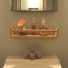 a bathroom sink under a mirror next to a shelf with soap and lotion on it