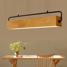 a wooden table and chair with a plant on it under a light fixture over the dining room table