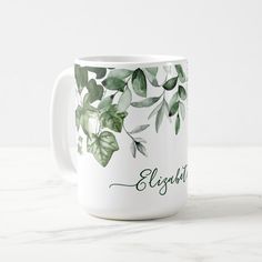 a white coffee mug with green leaves and the words, elizabeth on it's side