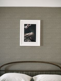 a bed with white pillows and a framed photograph on the wall