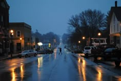 two people are walking down the street in the rain at night with their umbrellas open