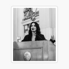 a black and white photo of a woman speaking at a podium