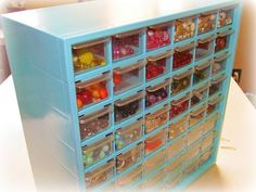 a blue toy storage unit filled with lots of small plastic containers and toys on top of a white table