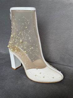 a white high heeled shoe with pearls on it