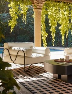 a living room with couches and tables in front of an open patio area that overlooks a swimming pool