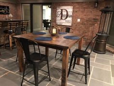 a dining room table with four chairs and a sign on the brick wall above it