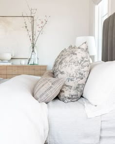 a bed with white linens and pillows on it's headboard in a bedroom