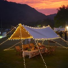 a large tent with lights on it in the middle of a field