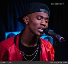 a man in a red jacket singing into a microphone