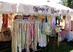 an outdoor market with lots of clothing hanging from it's sides and the words wings of blue above them