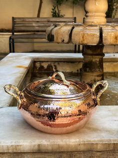 a large metal pot sitting on top of a stone slab