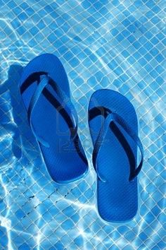 a pair of blue flip flops sitting on top of a swimming pool