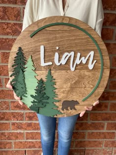 a person holding a wooden sign with the word lawn written on it and some trees