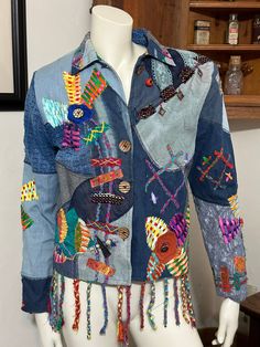 "Vintage 80's Sandy Starkman boho patch-worked denim jacket with embroideries and colorful appliqués. Shoulder pads. In excellent structural condition - a button is loose in the middle of the front flower, a closure button is missing - with so much going on with this awesome jacket, flaws are difficult to find. The fraying of the hanging braids at the bottom look like they're supposed to be that way. No stains or loose seams. Size M Chest: 21\" Length: 22\" not including braids See pictures I buy from estates sales, auctions, garage sales and thrift stores and do not claim to be an expert on any items. I try the best I can to describe the item as I see it. I test all items to the best of my ability. In some cases I may not be exactly sure how an item works, therefore; I will try to identif Patch Work Denim Jacket, Embroidered Multicolor Denim Jacket For Fall, Blue Long Sleeve Denim Jacket For Festival, Multicolor Cotton Denim Jacket With Long Sleeves, Winter Festival Denim Jacket With Patchwork, Bohemian Patchwork Denim Jacket For Fall, Fitted Bohemian Outerwear With Patches, Fitted Multicolor Denim Jacket For Festivals, Bohemian Cotton Outerwear With Patches